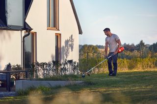 Акумуляторний садовий інструмент Husqvarna біля будинку